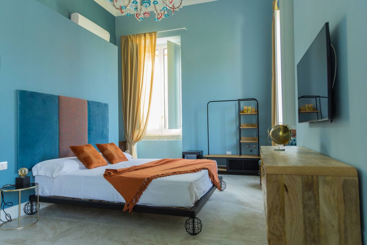 Ein Schlafzimmer mit einem Bett, einem Holztisch, einem Globus und einem Fernseher an der Wand.