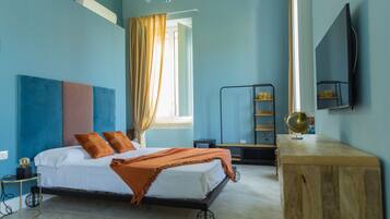 A bedroom with a bed, a wooden desk, a globe, and a TV on the wall.