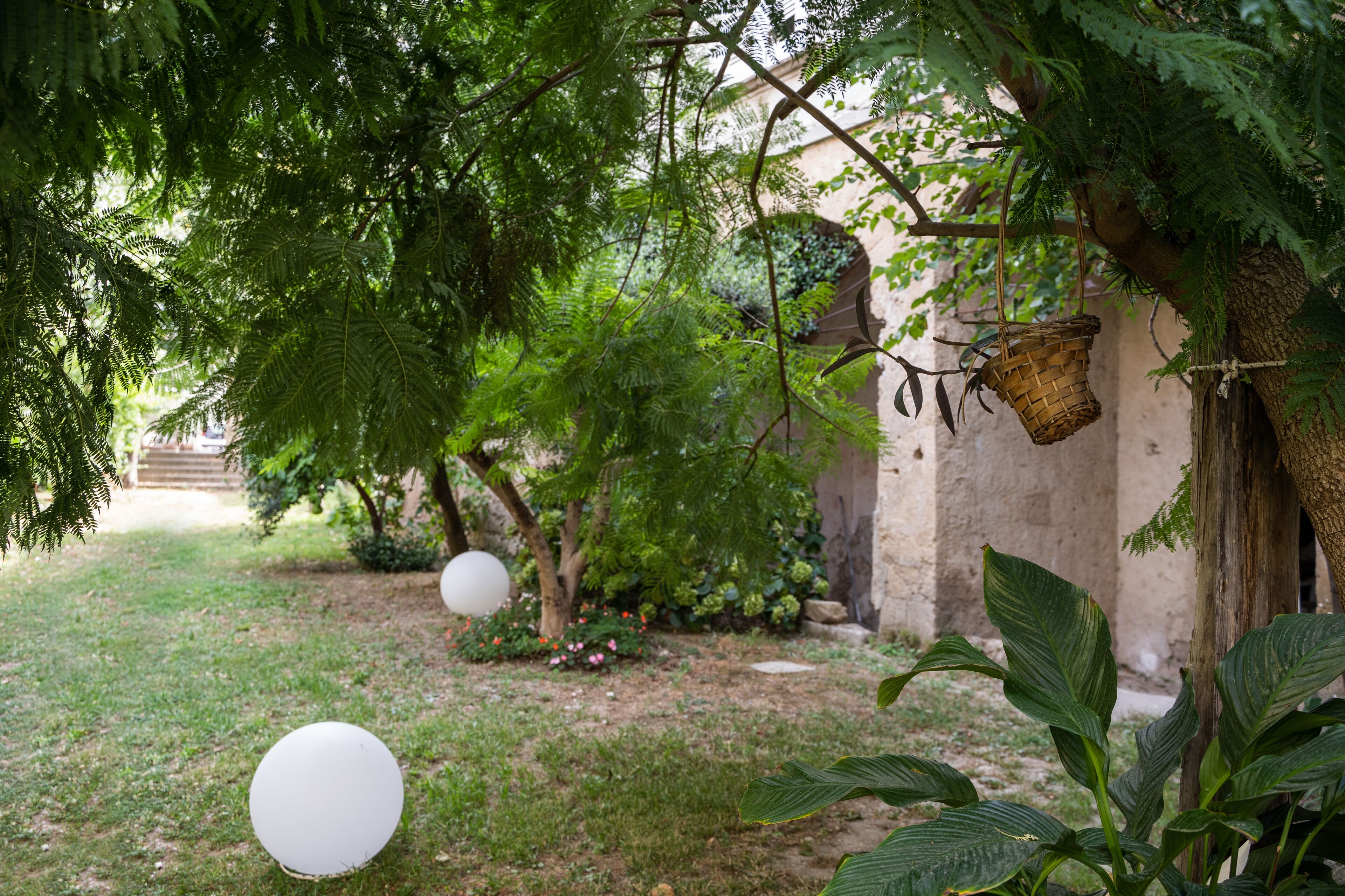 A garden with a pergola, white balloons, and lush greenery.