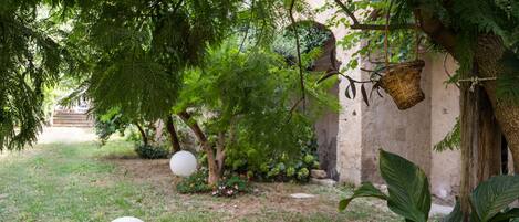 A garden with a pergola, white balloons, and lush greenery.