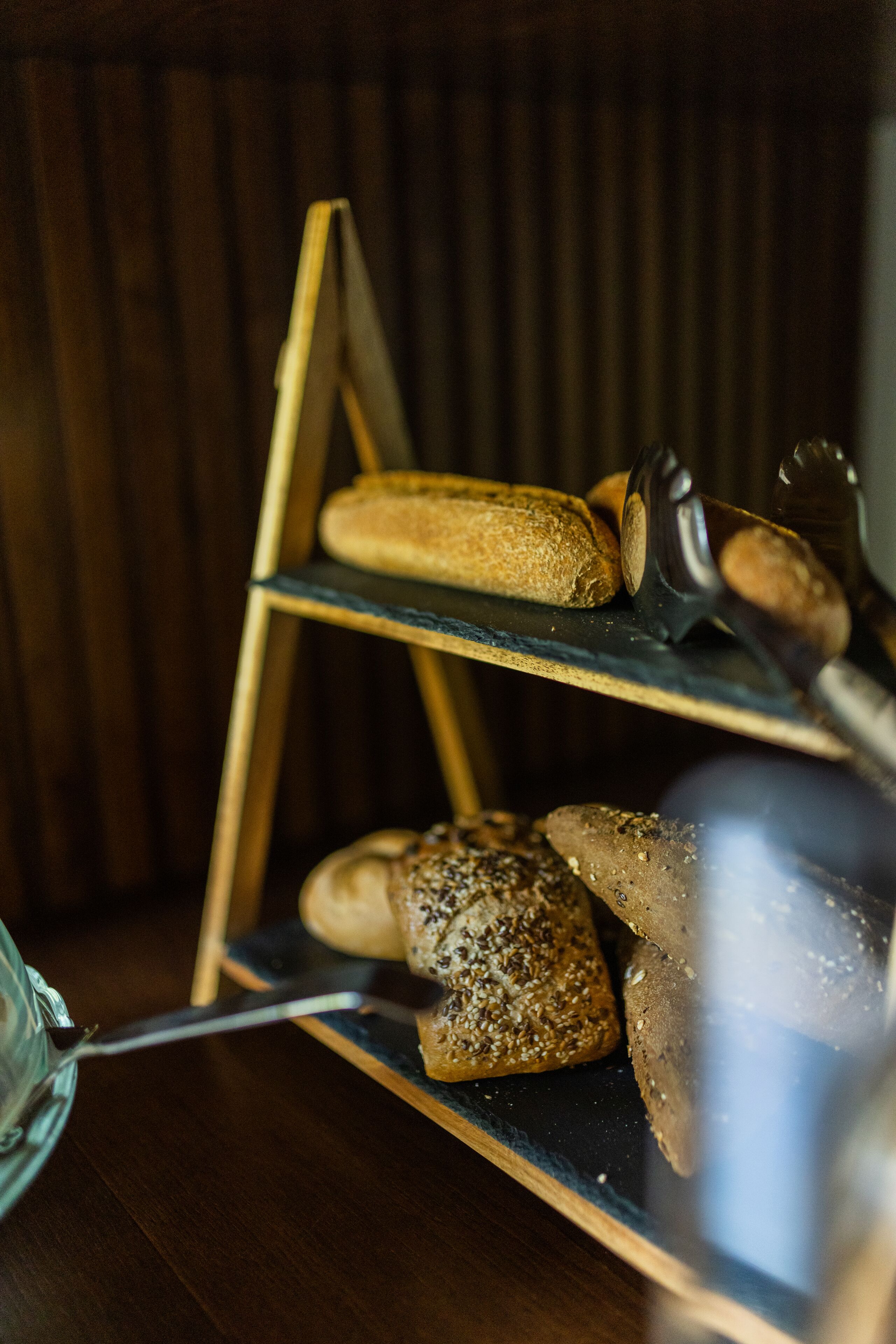 A wooden bread rack with various loaves of bread.