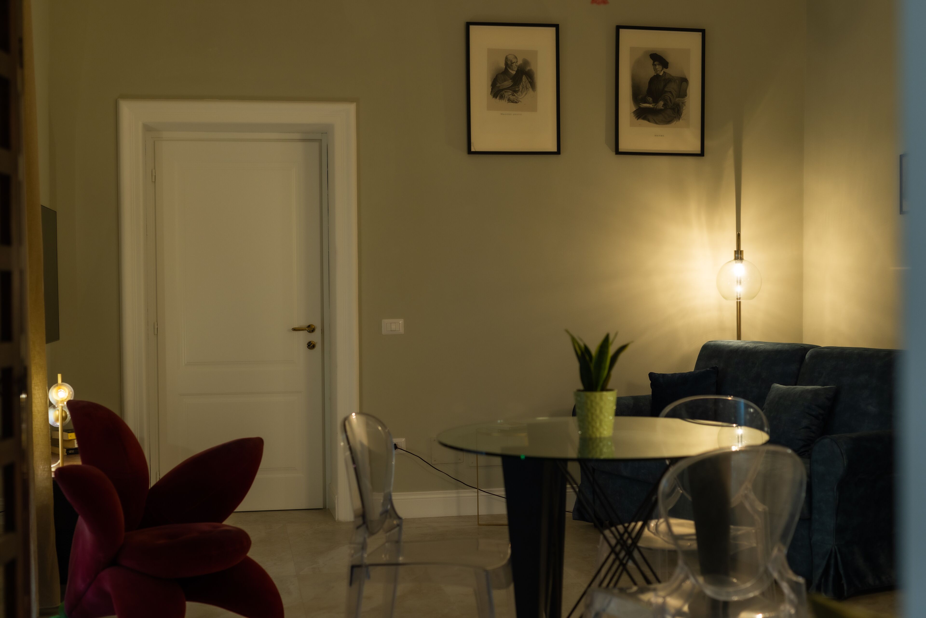 A dining area with a round table, chairs, a potted plant, and a sofa.