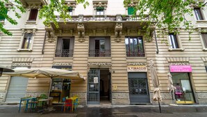 A building with a storefront, outdoor seating, and a sign for 'IL VINCIGUORI'. - Isola Cozy Apartment (Milan)