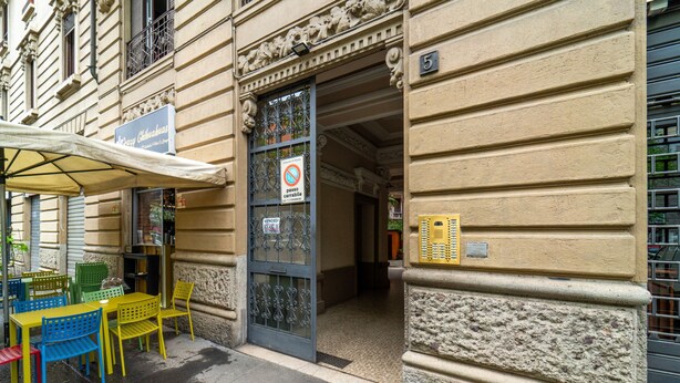 A building with a wrought iron gate, a sign reading "VENDES", and a number "5" on the wall. - Isola Cozy Apartment (Milan)