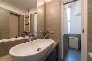 Ein modernes Badezimmer mit einem großen weißen Waschbecken, einem Spiegel und einem Handtuchhalter.