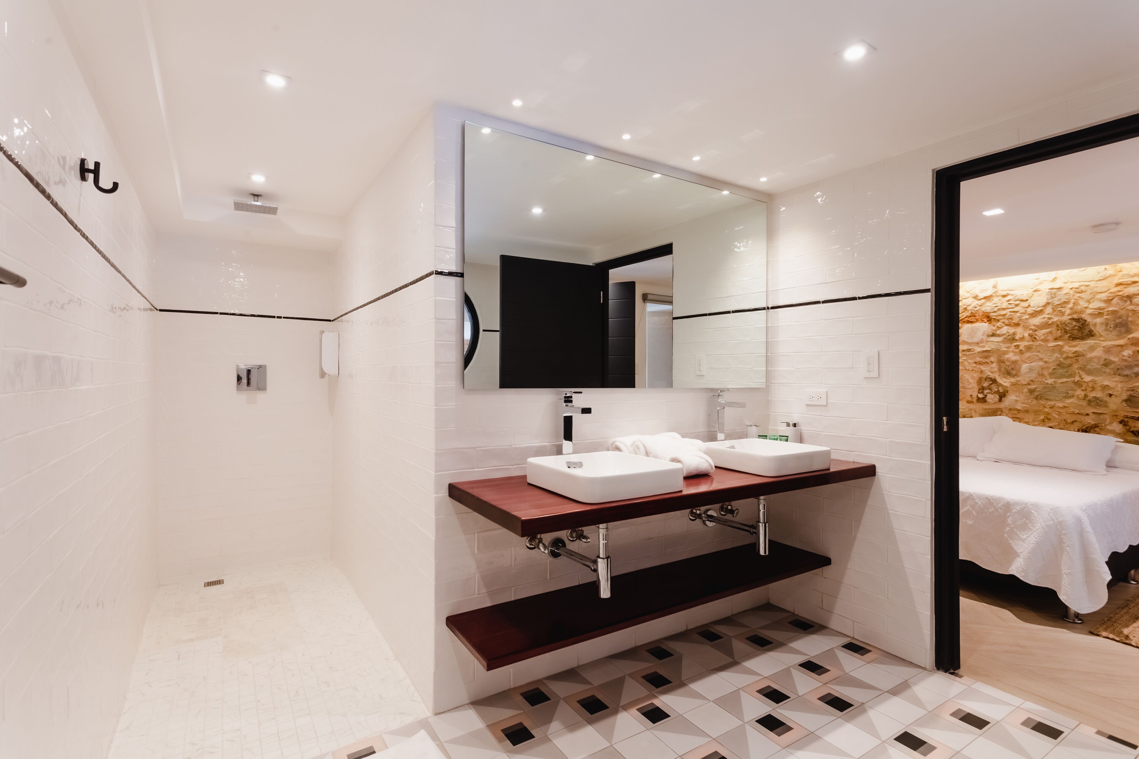 Een moderne badkamer met een grote spiegel, twee wastafels en een douche.