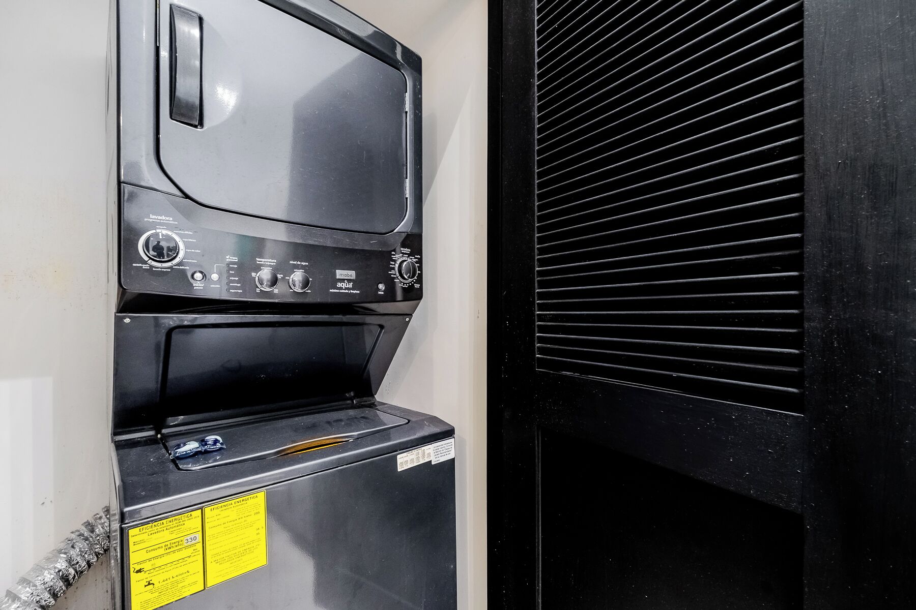 Una cocina comercial negra equipada con electrodomésticos de acero inoxidable, incluyendo una estufa y un lavacillos.