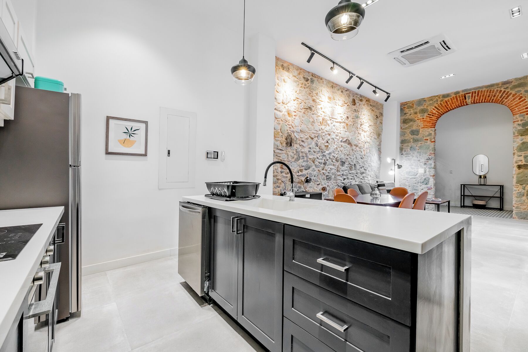A modern kitchen with a central island, stainless steel appliances, and a stone accent wall.