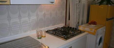 Una cocina compacta con estufa a gas, lavavajillas y lavadora.
