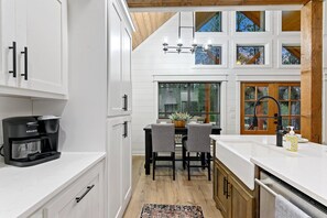 Enjoy a warm atmosphere in this kitchen with a coffee maker and views of the surrounding trees.