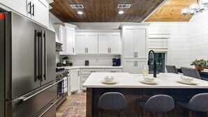 A modern kitchen with white cabinetry, a stainless steel refrigerator, and a central island with bar stools.