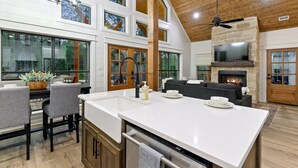A spacious kitchen with a large island, a fireplace, and a dining area with chairs and a table.