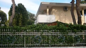 Ein Gebäude mit einer beigefarbenen Fassade, einem Balkon und einem weißen Zaun mit kreisförmigen Verzierungen.
