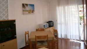 A dining area with a table and chairs, a microwave, and a television on a cabinet.