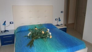 A bedroom with a bed, a nightstand, a lamp, and a door. - Residenz Silvida Wohnung A3 für 6 Personen (Bibione)