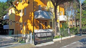 A yellow two-story building with a gated entrance and a small balcony. - Residenz Silvida Wohnung A3 für 6 Personen (Bibione)
