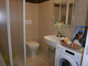 A compact bathroom with a toilet, sink, and washing machine.