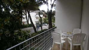 En balkon med gelænder i metal, hvide plaststole og et lille bord.