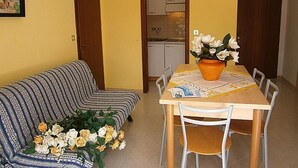 Ein Essbereich mit Tisch, Stühlen, einer Couch und einem Blumenstrauß.
