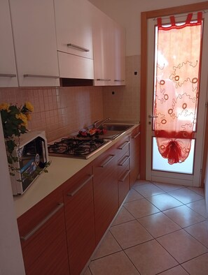 A kitchen with a gas stove, sink, and wooden cabinets.
