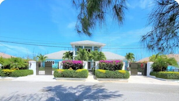 A two-story building with a flat roof, surrounded by well-maintained hedges and flowering plants. - Ocean villa (Nassau)