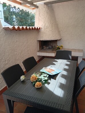 An outdoor patio with a table, chairs, and a built-in grill.
