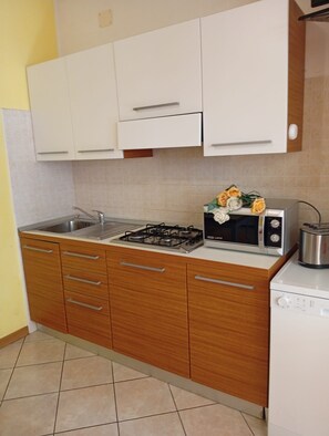 A kitchen with white cabinets, a gas stove, a toaster, and a sink.