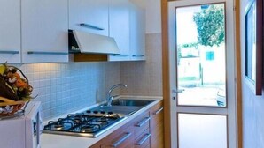 A compact kitchen with white cabinets, a gas stove, and a sink.