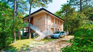 A two-story building with a staircase leading to the entrance, surrounded by trees and greenery. - Residenz Elia Wohnung Bilo Erdgeschoss für 5 Personen (Bibione)