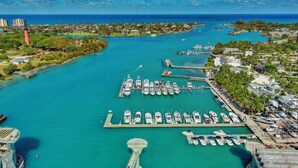 An aerial view of a marina with boats docked, a lighthouse, and a bridge connecting to the mainland. - Lucky Landing's (Jupiter)