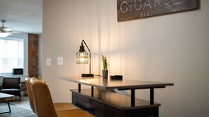 A modern dining area with a table, chairs, a pendant light, and a wall-mounted sign. - Rhythm Loft Above the Honky Tonk (Saint Charles)