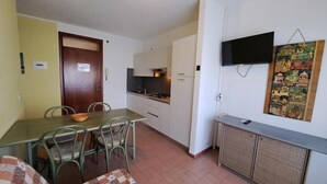 Una cocina compacta con comedor, un televisor montado en la pared y una obra de arte con diseño.