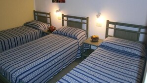 Una habitación con dos camas individuales, cada una con cabecero y una mesita de noche. Hay lámparas de pared sobre las camas.