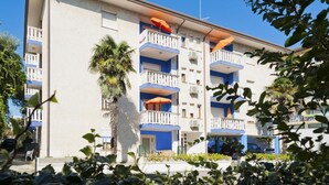 Un edificio de varios pisos con balcones, algunos con sombrillas.