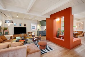 Relax in this spacious living area with a large flat-screen TV, comfortable seating, and a dining table.