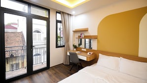 A hotel room with a bed, a desk, and a balcony. - Fusion Gates Apartment (Hanoi)