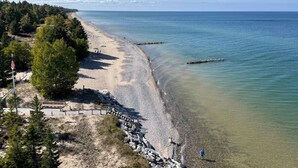 A beach with a rocky shoreline, a wooden walkway, and a flag. - Crisp Point Beach Cabin (Newberry)