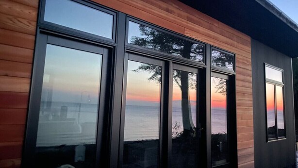 A modern building with large windows and a view of the ocean. - Crisp Point Beach Cabin (Newberry)