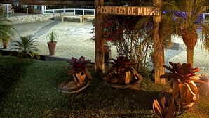 Un letrero de madera con los nombres 'POUSADA' y 'ACONCHO DE MIMI' que indica una zona de hospedaje.