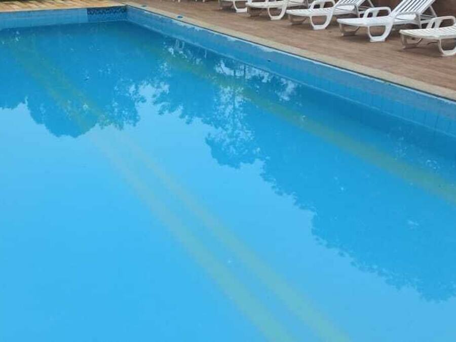 Una piscina con agua azul cristalina, rodeada de sillas reclinables blancas.