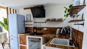 Eine kompakte Küche mit integriertem Geschirrspüler, Spüle, Holz Arbeitsplatten und einem an der Wand montierten Fernseher.