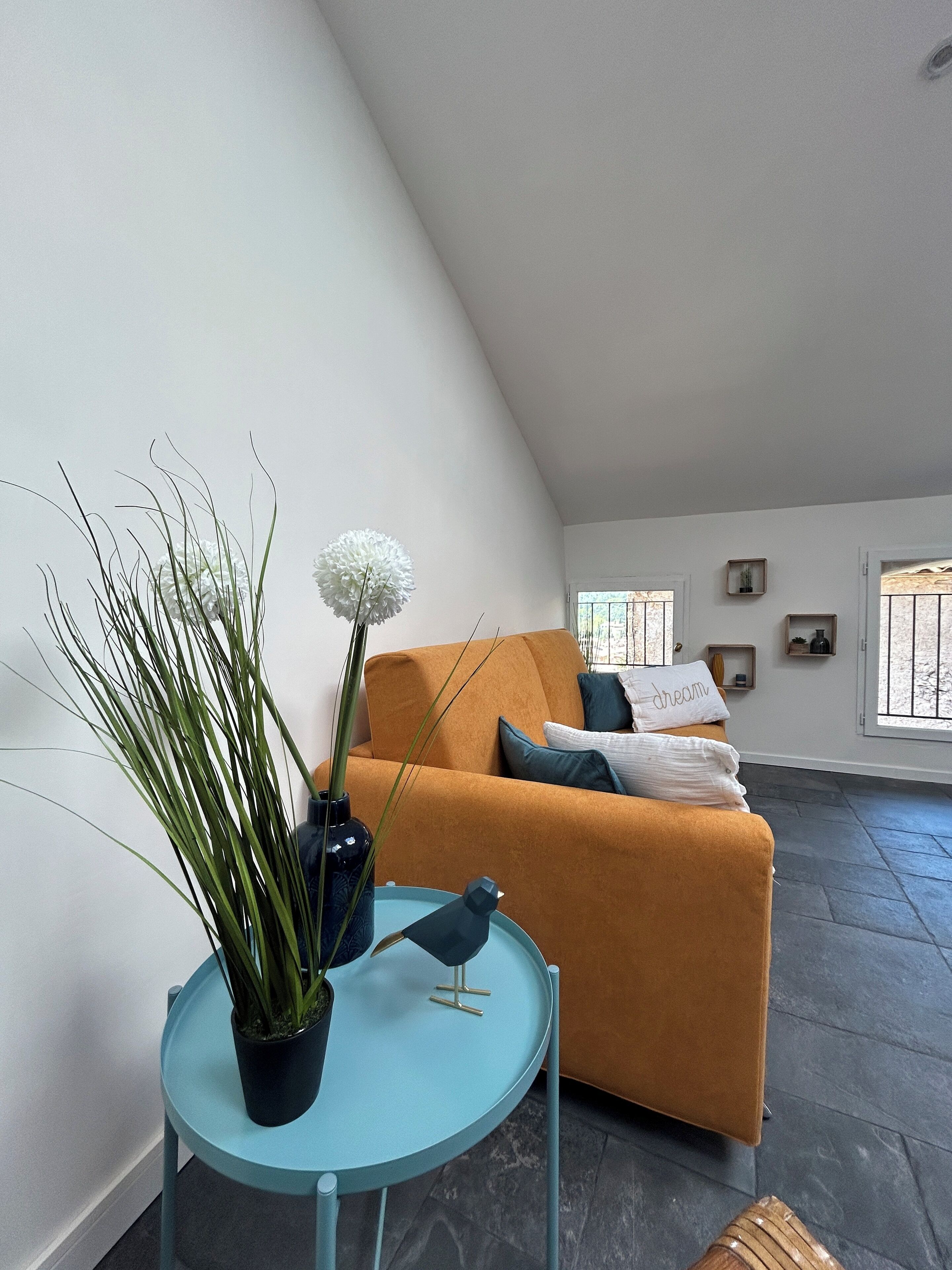 Una sala de estar moderna con un sofá, una mesa redonda con una planta y una escultura decorativa de un pájaro.