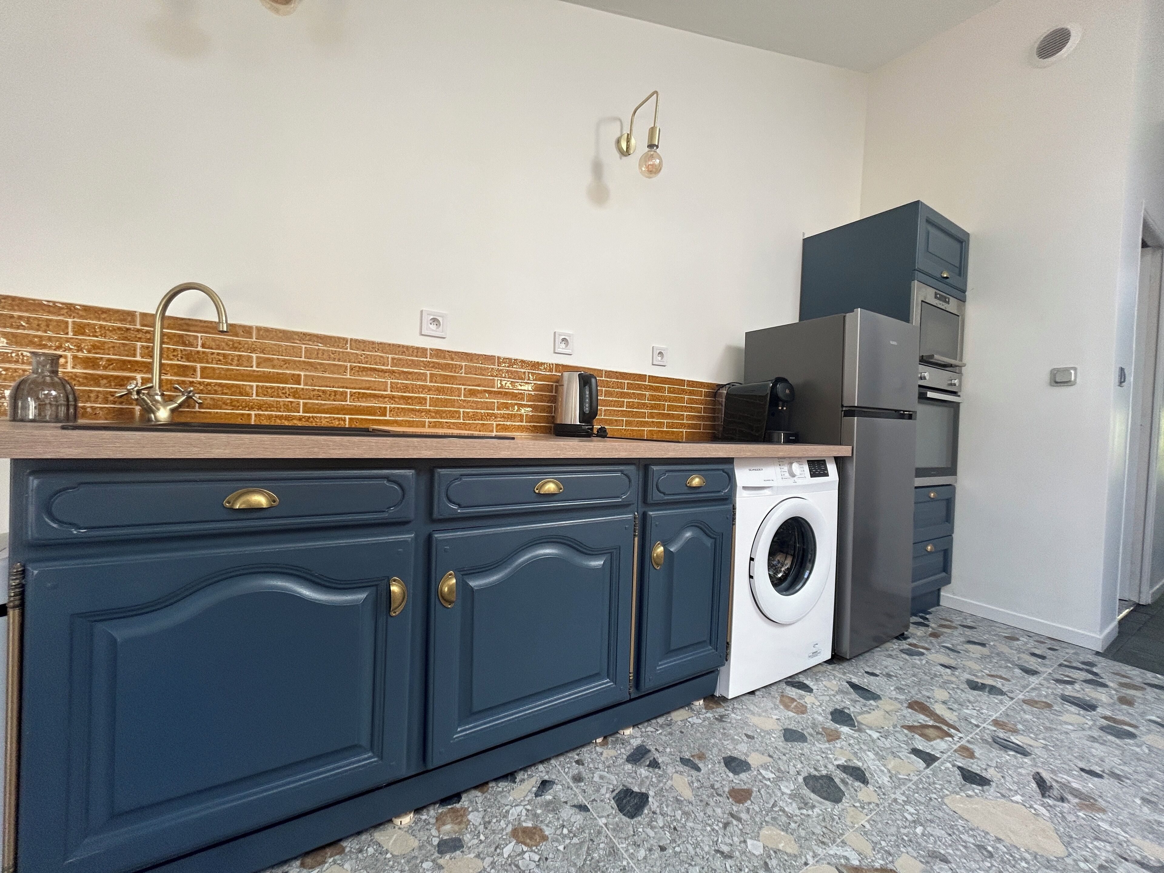 A compact kitchen with a washing machine, a built-in oven, and a microwave.