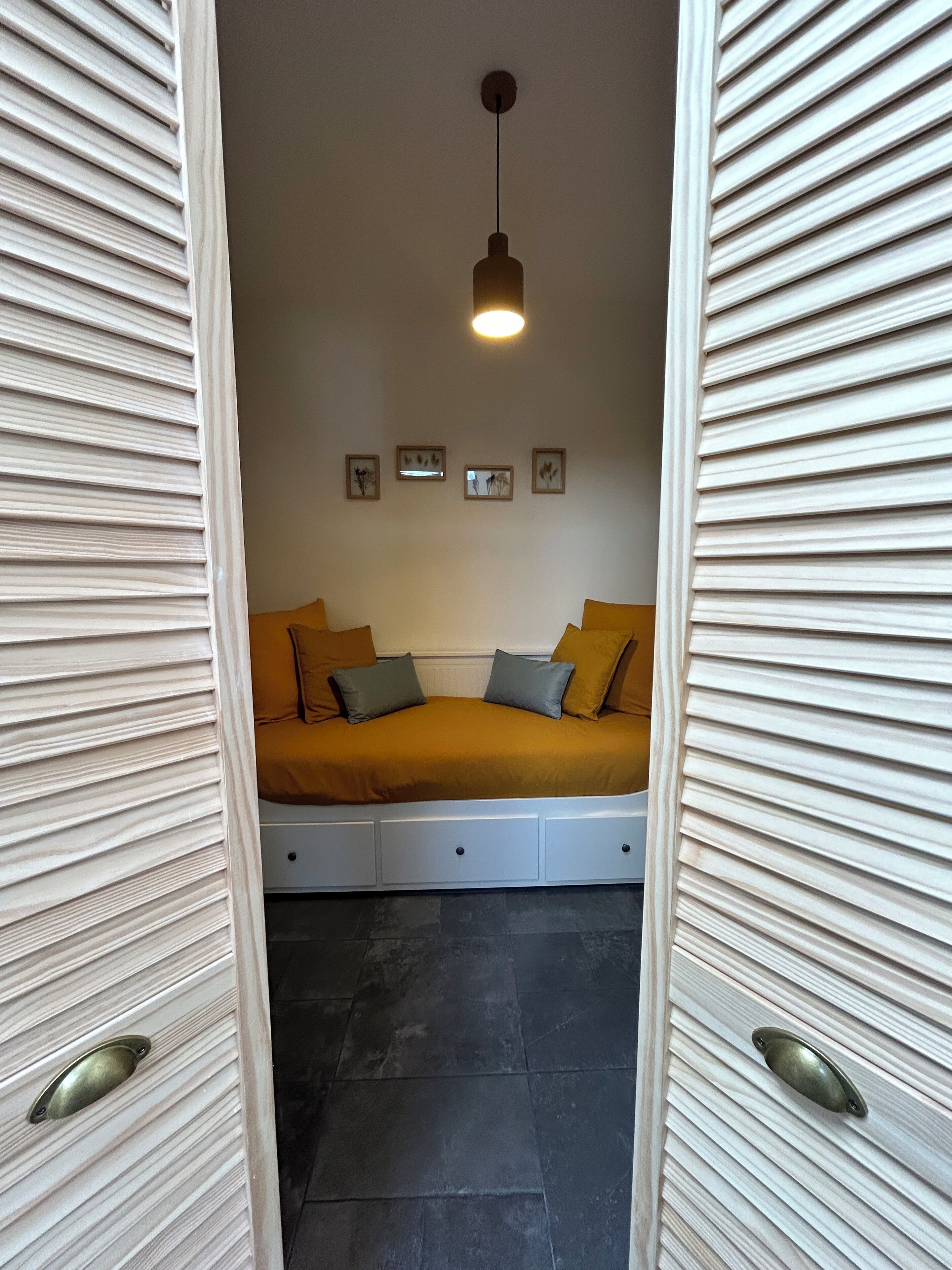 Une chambre à coucher avec un lit, un luminaire suspendu et un mur orné de tableaux encadrés.
