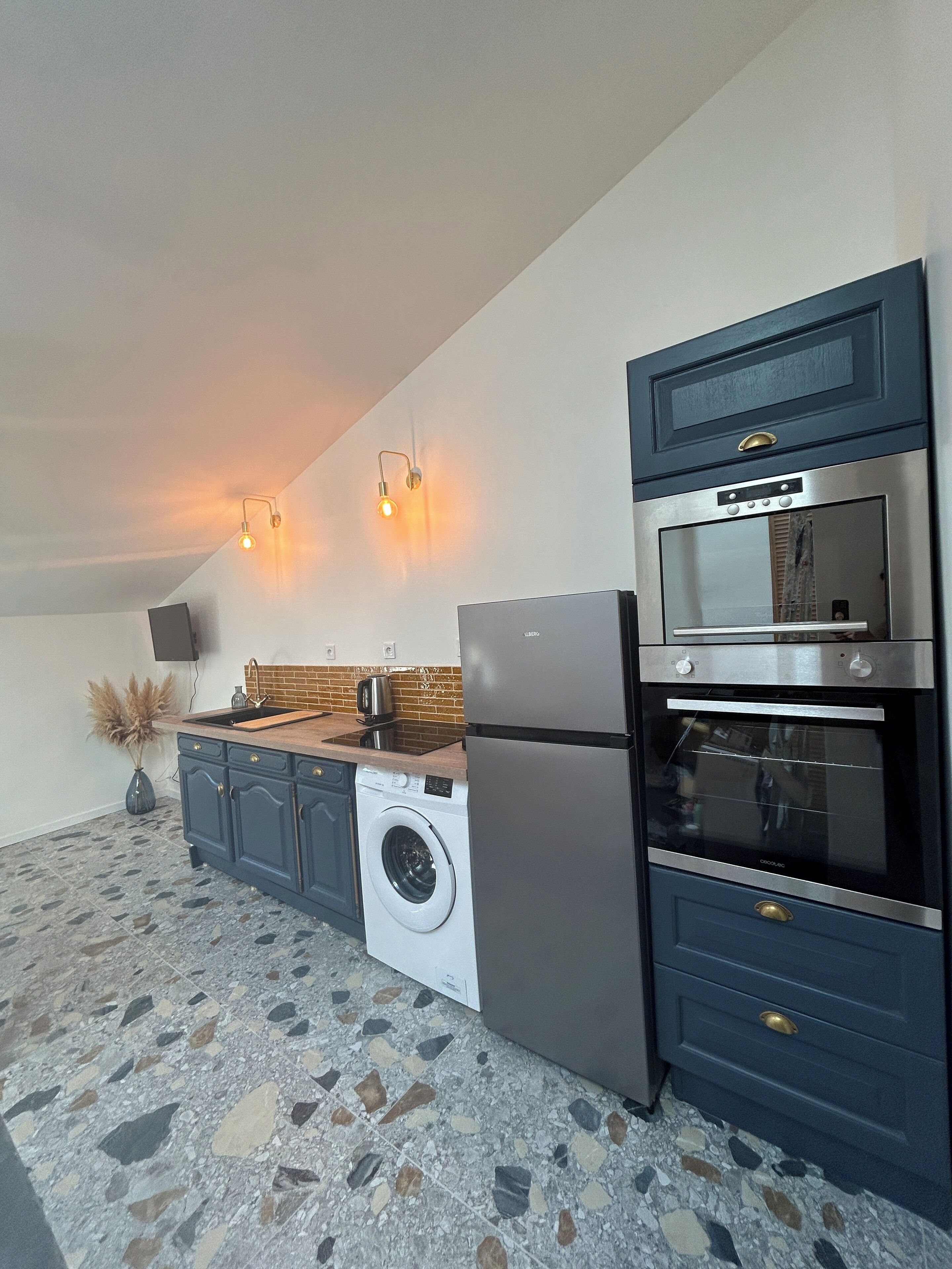 Una cocina moderna con lavadora, refrigerador, horno y lavamanos.