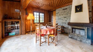 Ein Holzinnenraum mit Kamin aus Stein, einem Esstisch mit Stühlen und einer Lampe.