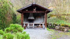Eine rustikale Holzhütte mit Schornstein, Holzbanken und einer Steinmauer.