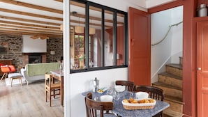 Un espace repas agrémenté d’un mur en pierre, de poutres en bois au plafond et offrant une vue sur un escalier.