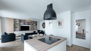 Een moderne keuken met een centraal kookeiland, inbouwapparatuur en een grote zwart pendelarmatuur.