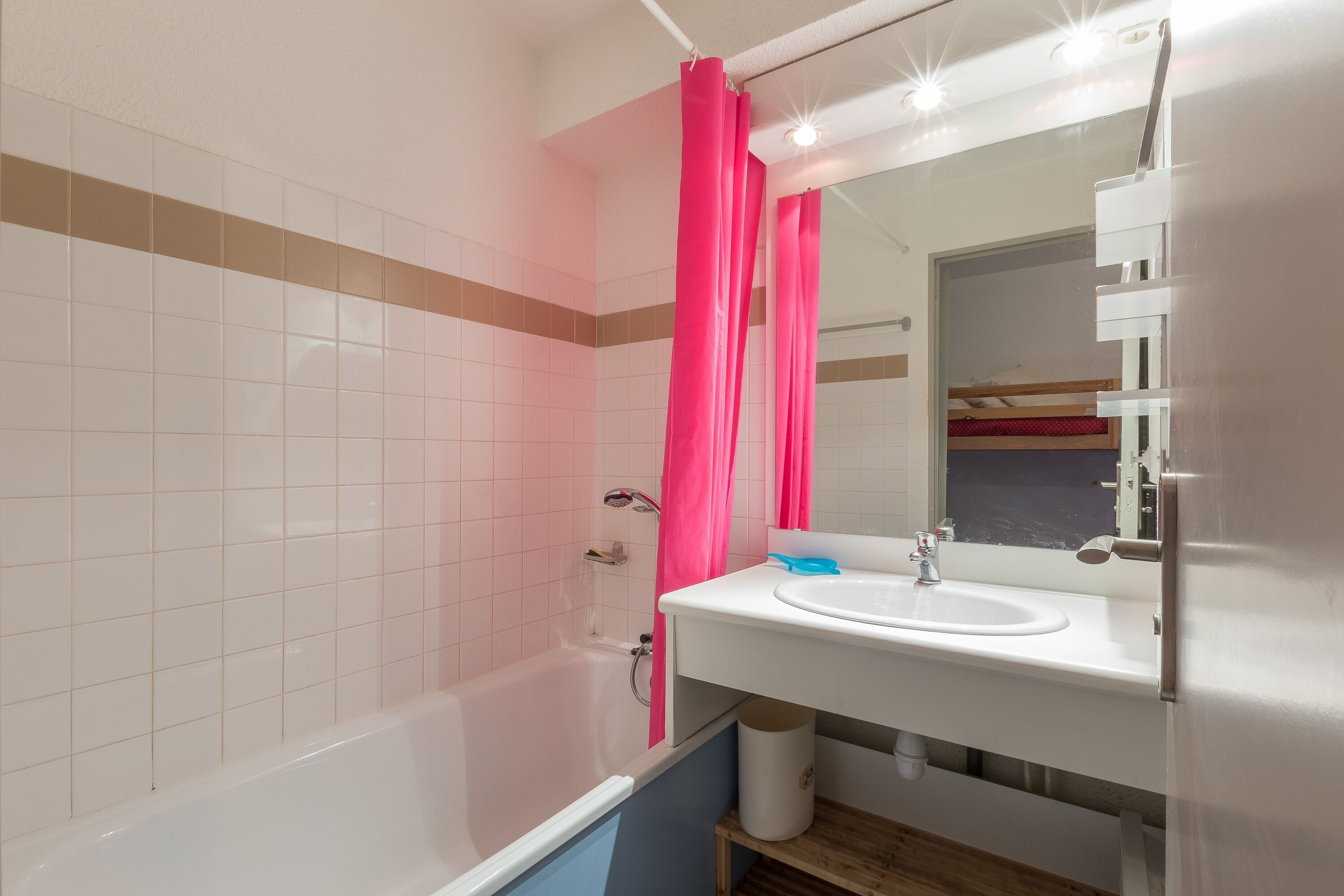 A bathroom with a white sink, mirror, and pink shower curtain.